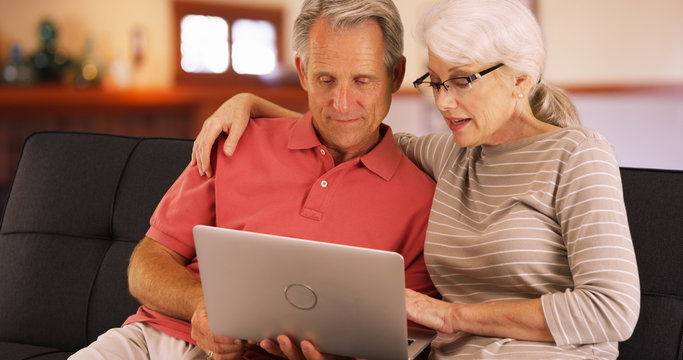 Closeup of older couple using laptop at home