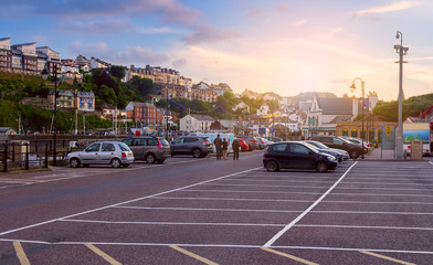 Car parking at the harbor in the town of Ilfracombe. Walking people. Many houses on the hill.  North Devon. UK