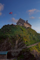 Little church on the top of the mountain. Flag of Great Britain on the mast. Near the town of Ilfracombe. North Devon. UK
