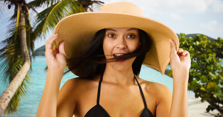 Young white girl in a sun hat poses for a portrait on a Caribbean beach