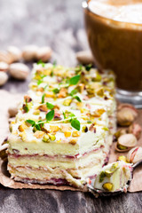 Slices  of layered cake with pistachio and a cup of coffee with