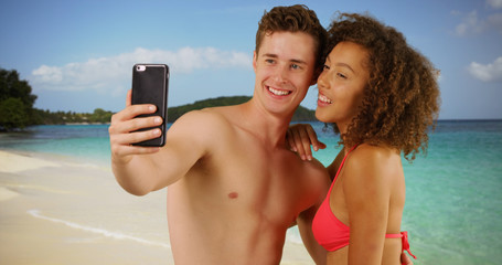 Happy couple using smartphone to take selfie.