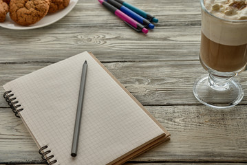 Blank notebook, pencil and cup of coffee on a wooden background