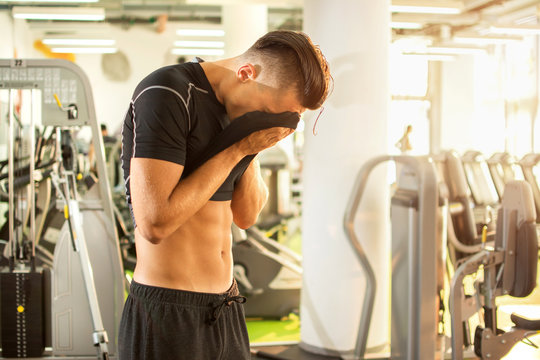 Athletic Man Wiping Sweat After Hard Workout In Gym.