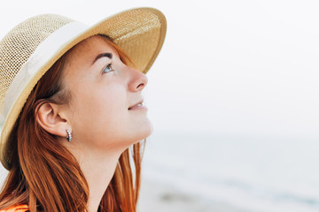Portrait of a woman in a straw hat looking up on a background of the sea