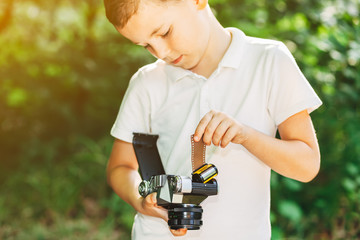 Little kid boy with retro photo camera standing in the green park on s sunny day. Outdoors. Young photographer. Close up