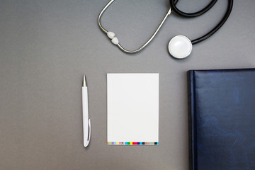 glasses, stethoscope and a notebook on a gray background, concept