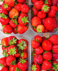 Plastic box package of red fresh strawberries on a wood box, top view
