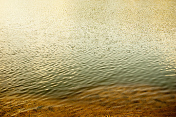 Riverbank, sand and rippled water with reflections a lot of copyspace