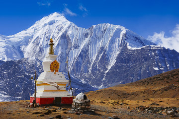 Buddhist stupa at Annapurna Circuit Trek with white summit view, Himalaya mountains, Nepal, Asia. For horizontal postcard or calendar.
