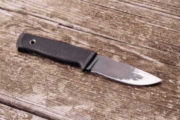 Black knife on wooden background.