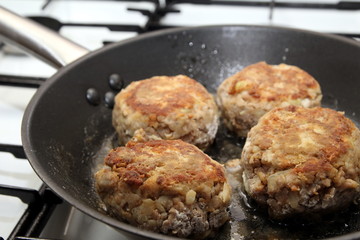 Rissoles, made from minced meat, onion and breadcrumbs, frying in a pan