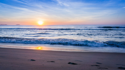 Pegadas na praia ao nascer do sol