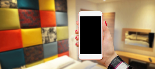 Women holding phone in hand, in bedroom with colorful background