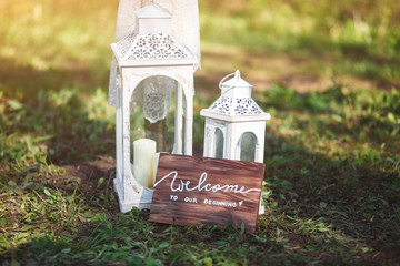 A wooden plate with the words "Welcome to our beginning" and white candles. Wedding concept