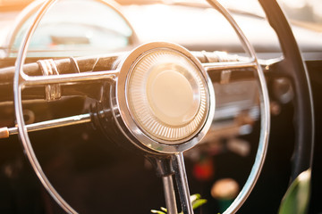 Black steering wheel and dashboard of the vintage car. Close up