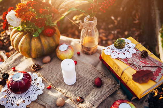 Romantic autumn scenery for photo shoots. Old books, flowers, pumpkins, apples and candles