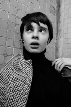 portrait of a beautiful young girl with short hair near the window in a jacket, fashion