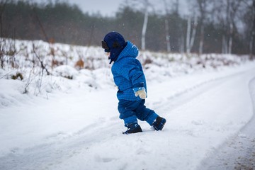 Fototapeta na wymiar Happy little boy playing outdoor in winter snow