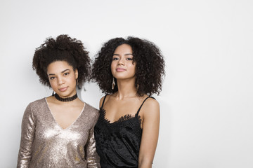 Portrait of two women against white wall, looking at camera