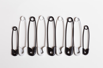 White and Black safety pins on white background