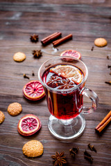 mulled wine with spices in cup on wooden background