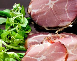 Crude, dried bacon or ham with sandwich, vegetables and herbs on wooden board