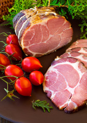 Crude, dried bacon or ham with vegetables and herbs on wooden board