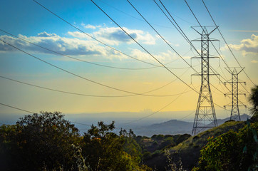 Sunset in the mountains over power lines with downtown Los Angeles skyline ithe the background. - Powered by Adobe