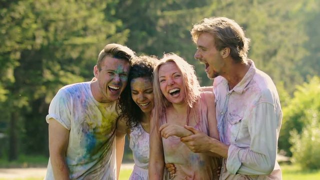 Laughing faces of soaking wet excited friends celebrating Holi color festival