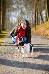 Naklejka na ściany i meble People and dogs outdoors. Beautiful and happy woman enjoying in autumn park walking with her Jack Russell terrier..Colored photo