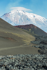 The active lava flow from a new crater on the slopes of volcanoes Tolbachik, on background...