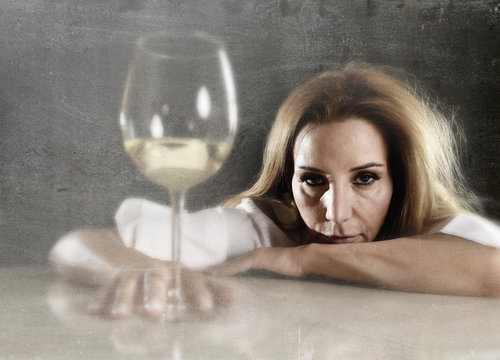 wasted alcoholic woman depressed looking thoughtful with white wine glass