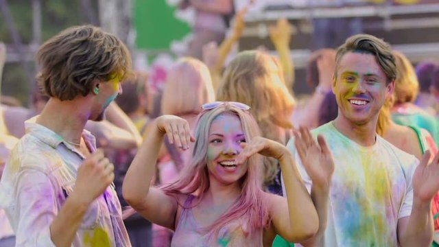 Funny excited youngsters actively dancing at Color festival, extra-slow motion 