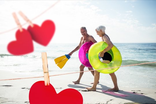 Senior couple with swim ring and swimfin walking on beach