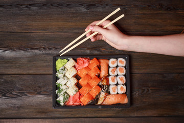 dishes of traditional Japanese cuisine and hand with wooden chopsticks