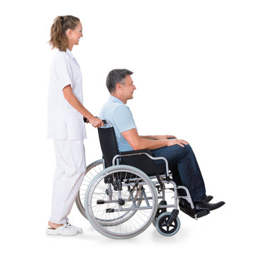 Caretaker Pushing Disabled Patient On Wheelchair