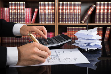 Judge Calculating Invoice In A Courtroom