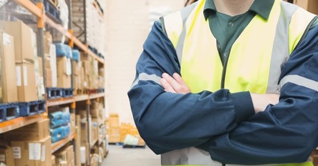 Mid section of supervisor standing with arms crossed