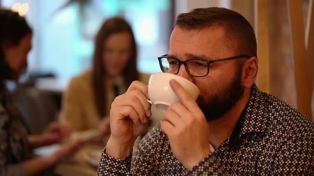Penscive handsome man smiling and drinking caffee in a cafe
