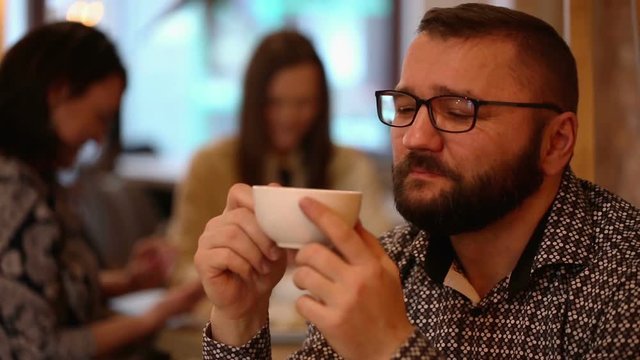 Happy, young handsome man smiling and drinking caffee in a cafe

