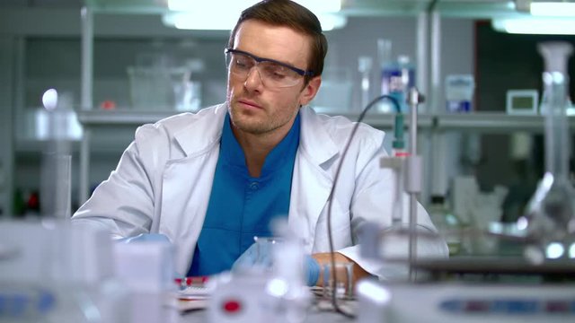 Scientist in lab. Scientist looking at chemical liquid in research laboratory. Scientist working in laboratory with chemical reagents. Lab man carrying out scientific research in lab. Scientist lab