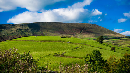 Z-shape uphill country road, Pendle Hill in distance, Summer,blue sky and white clouds, 16:9 aspect...