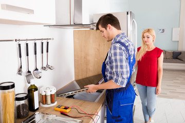 Repairman Examining Stove In Kitchen
