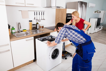 Male Worker Repairing Washer In Kitchen Room