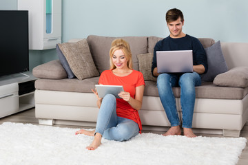 Couple Using Digital Tablet And Laptop At Home