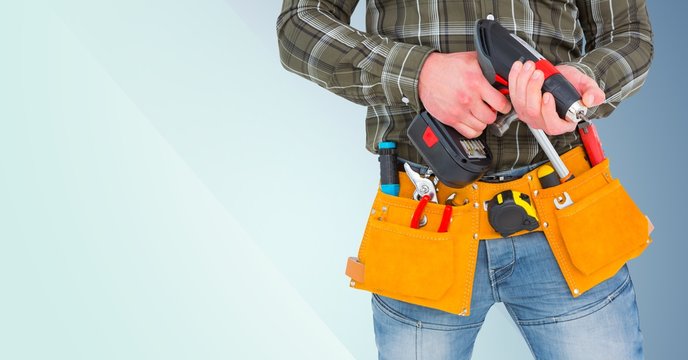 Mid section of handyman holding drill machine and plank