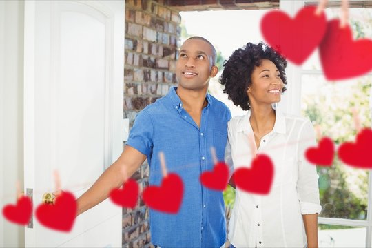 Composite Image Of Red Hanging Hearts And Couple Entering Home 