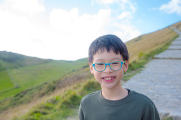 Young asian boy smiling with hill in background