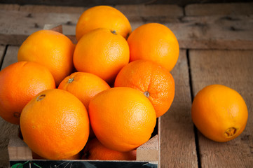 Fresh whole oranges in a box on a wooden background